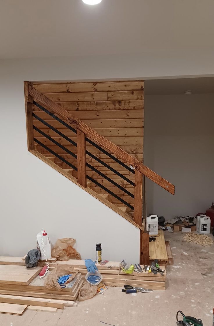 an unfinished room with wooden stairs and construction materials on the floor in front of it