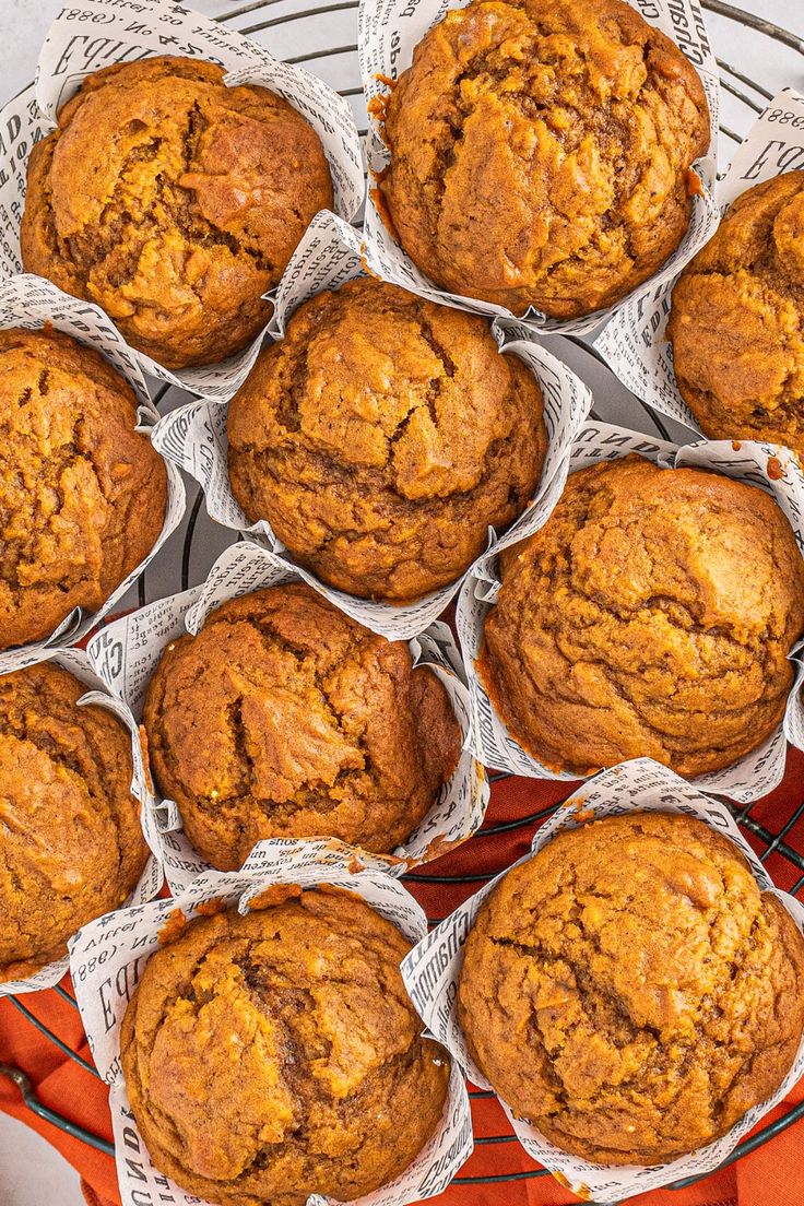 several muffins sitting on top of each other in paper wrappers next to an orange napkin