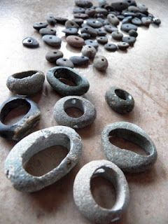 several pieces of ancient pottery sitting on a table next to rocks and pebbles in the shape of rings