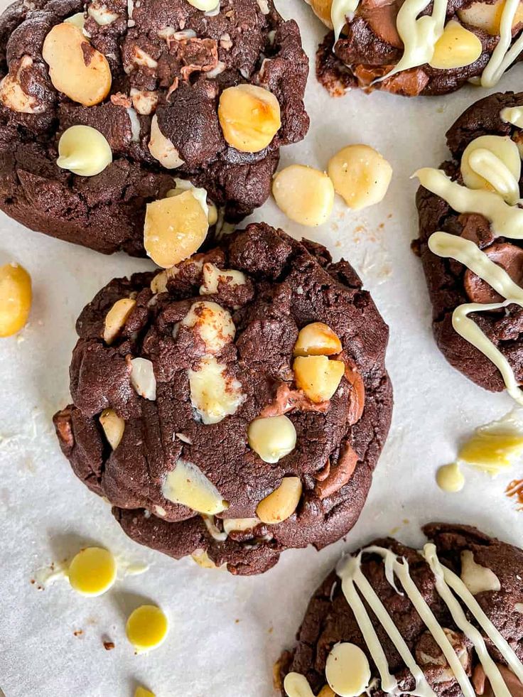 chocolate cookies with macaroni and cheese drizzled over them on a sheet of parchment paper