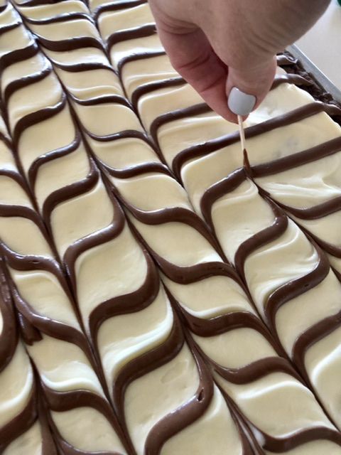 a person is decorating some kind of cake with white icing and chocolate on it