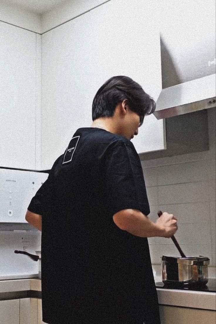 a man standing in a kitchen preparing food on top of a stove next to an oven