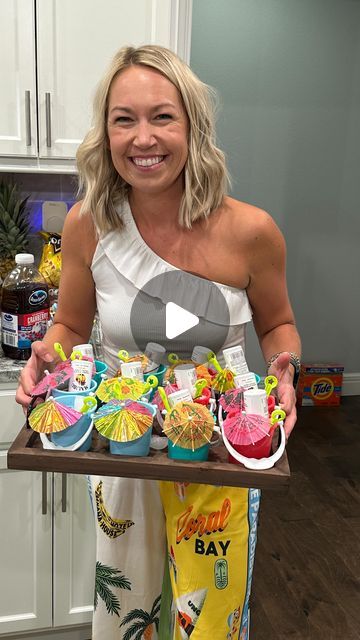 a woman holding a tray full of cupcakes