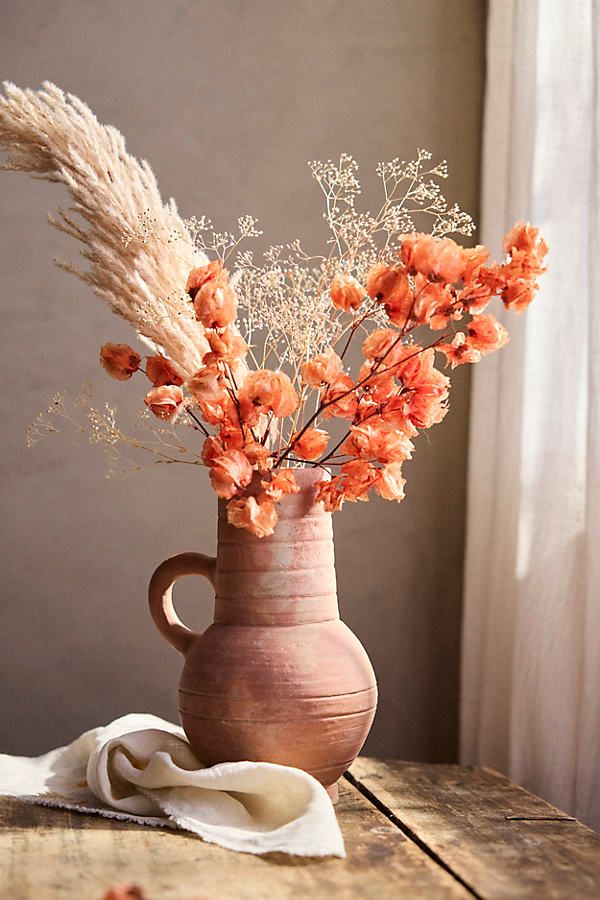 a vase filled with flowers sitting on top of a wooden table next to a window