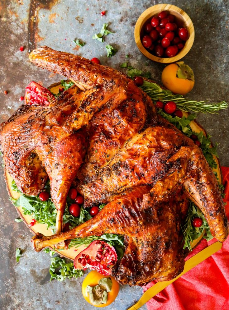 roasted turkey with cranberries and oranges on a platter next to a bowl of cherries