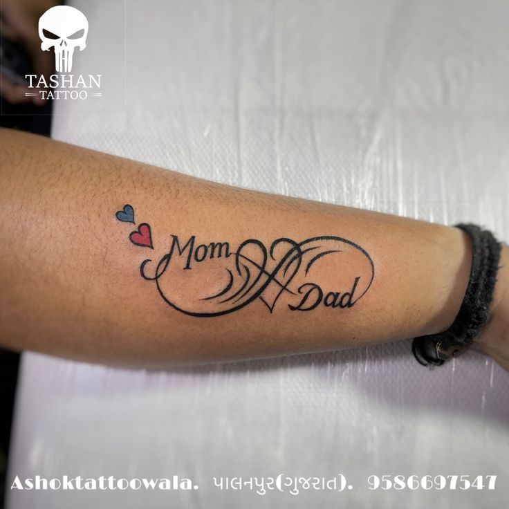 a woman with a tattoo on her arm that says, mom and dad in cursive writing