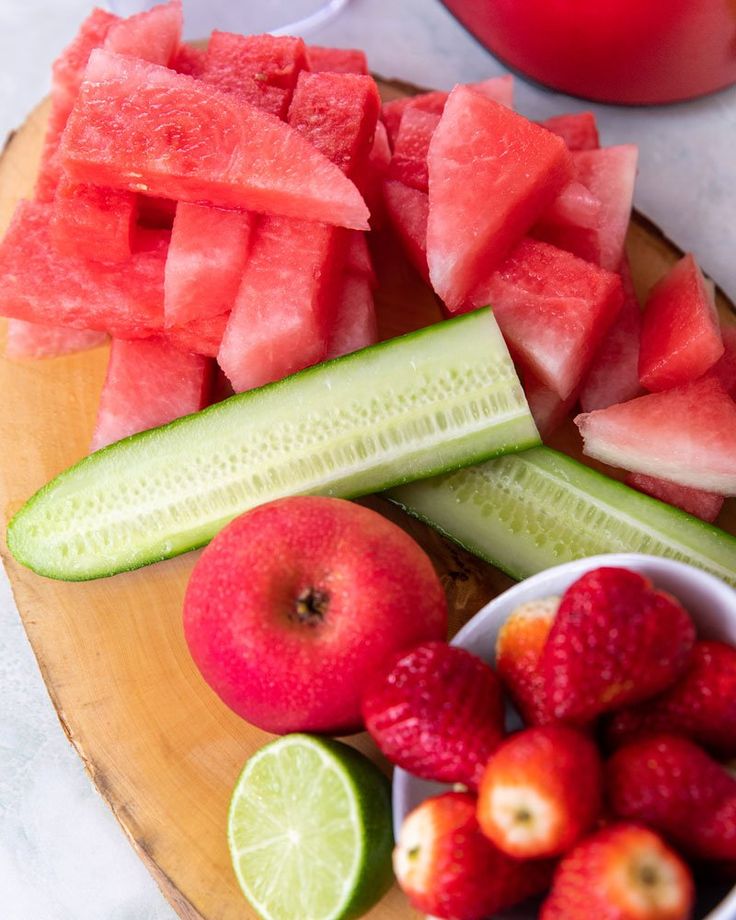 sliced up watermelon, cucumber and strawberries on a wooden plate