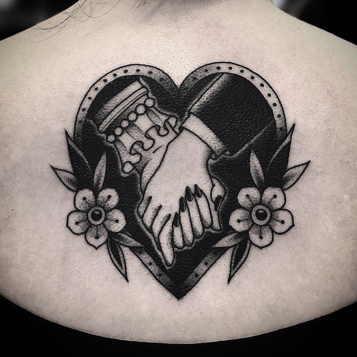 a black and white image of two hands shaking over a heart with flowers on it