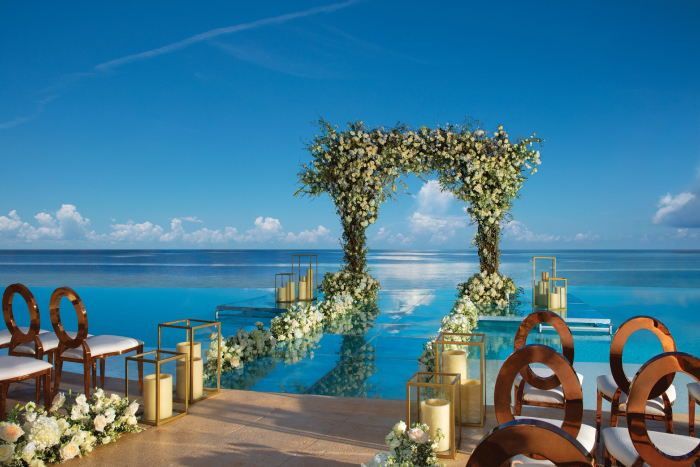 an outdoor wedding set up with chairs and flowers on the side of the pool, overlooking the ocean