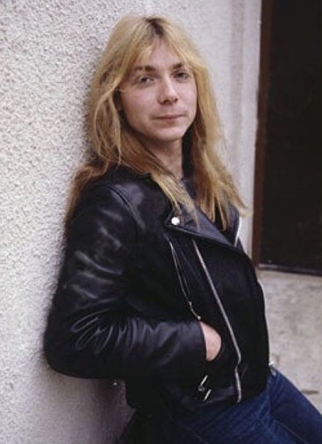 a woman leaning against a wall wearing a black jacket