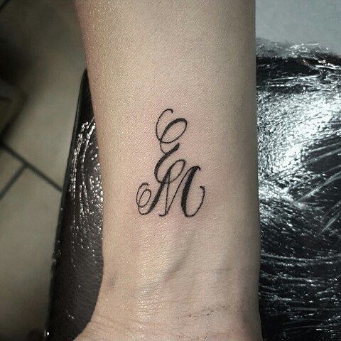 a small wrist tattoo with the letter m in cursive font on it's side