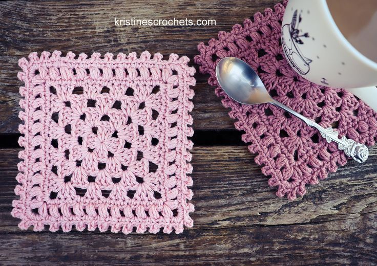 two crocheted placemats on a wooden table next to a coffee cup