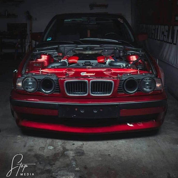 a red car parked in a garage with its hood up