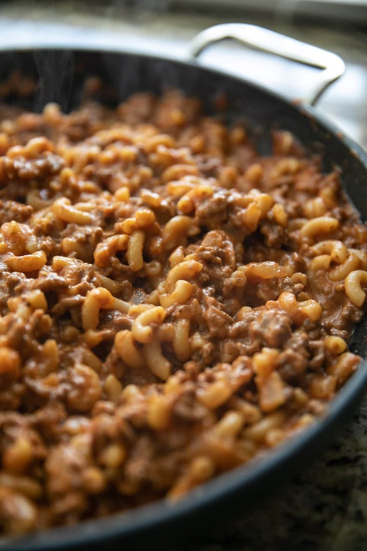 a skillet filled with macaroni and cheese on top of a stovetop