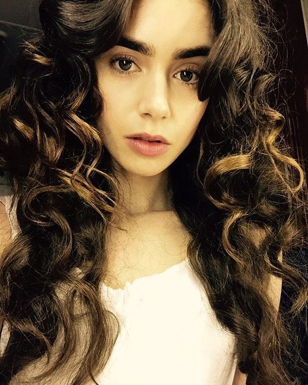 a young woman with long curly hair is taking a selfie