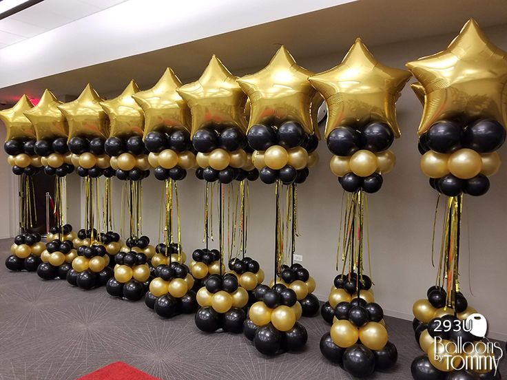 black and gold balloons are lined up against the wall