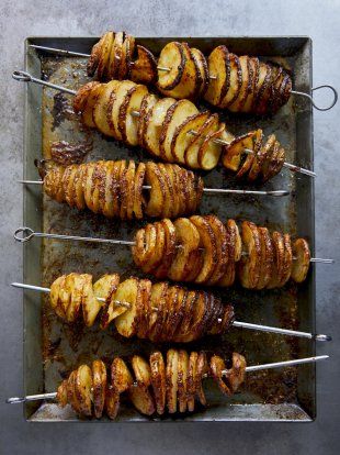 several skewered potatoes are on a baking sheet and ready to be grilled