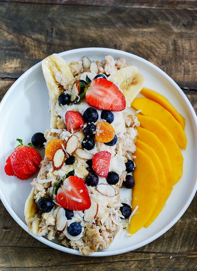 a white plate topped with fruit and granola next to sliced oranges on top of a wooden table