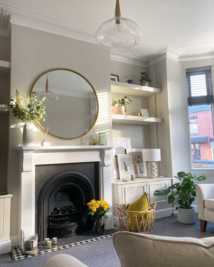 a living room filled with furniture and a fire place in front of a mirror on the wall