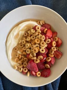 a bowl filled with cereal and strawberries on top of a blue cloth covered table