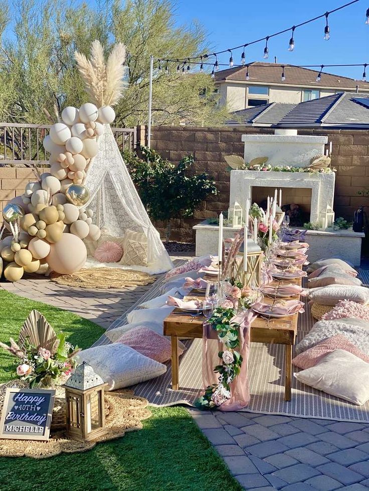 an outdoor party setup with balloons, pillows and other decorations on the grass in front of a house