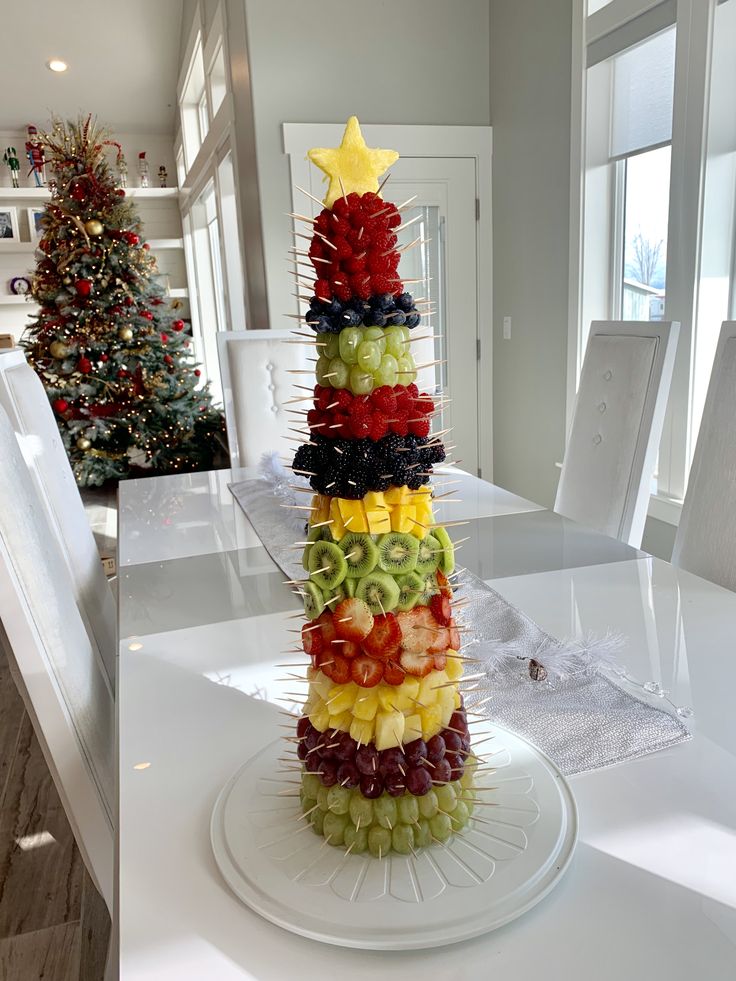 a christmas tree made out of fruit on top of a white table in front of a christmas tree