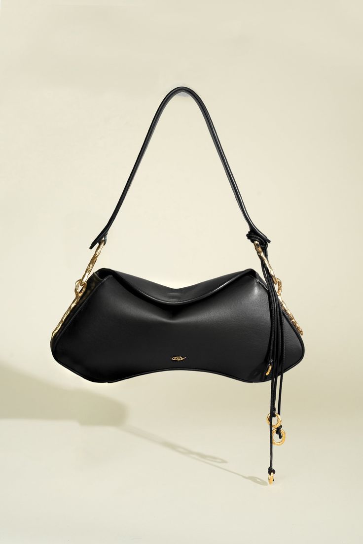 Distinguished by its hourglass silhouette, the Deià bag is handcrafted in Spain and features a structured frame and soft, fold-over flap with magnetic closure. Its timeless form is accented by hand-tooled 24k gold-plated hardware with irregular contours echoing nature’s organic elegance. The spacious interior is lined with soft cotton twill and contains a convenient leather pocket. This version is made from buttery soft Italian nappa leather and features a wide leather shoulder strap. It is orna Luxury Shoulder Bag With Pebbled Texture, Luxury Pouch Shoulder Bag With Leather Lining, Luxury Black Bags With Soft Leather, Luxury Black Shoulder Bag With Reinforced Handles, Luxury Flap Bag With Smooth Grain, Luxury Elegant Shoulder Bag With Grained Texture, Luxury Designer Shoulder Bag With Detachable Handle, Luxury Black Pebbled Leather Shoulder Bag, Luxury Staud Shoulder Bag With Detachable Handle