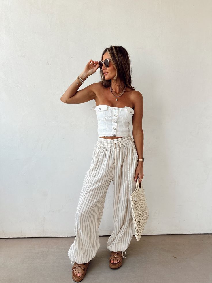 a woman standing in front of a white wall with her hand on her head and wearing sunglasses