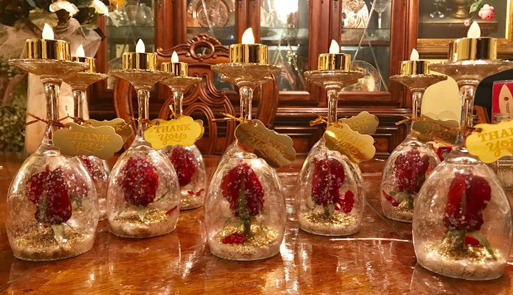 snow globes with strawberries in them sitting on a table next to candles and other decorations