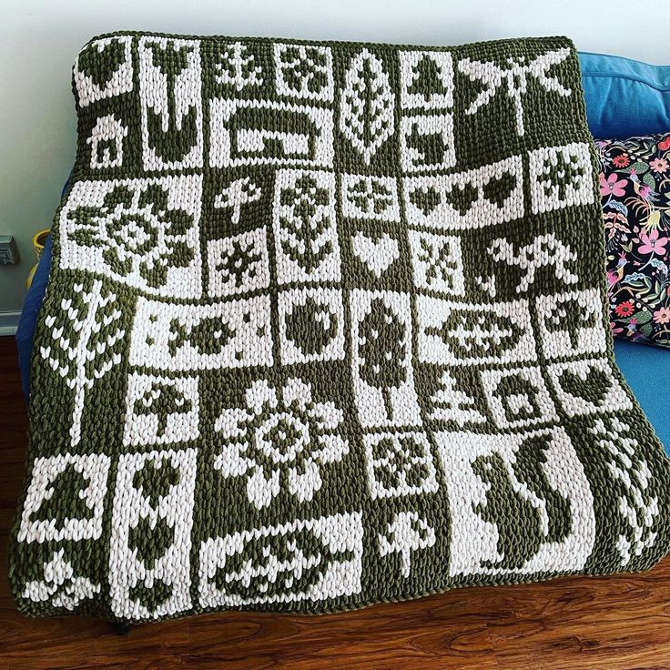 a crocheted blanket sitting on top of a blue couch next to a pillow