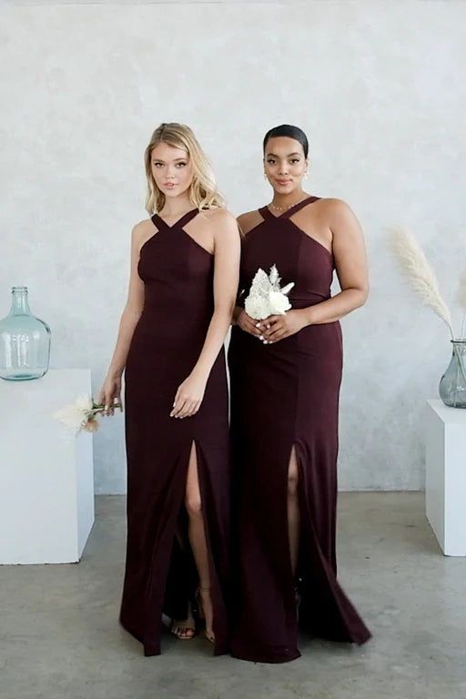 two women in dresses standing next to each other with vases and flowers behind them