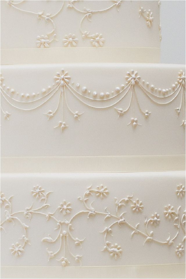 three tiered wedding cake with white icing and flowers on the top, side by side