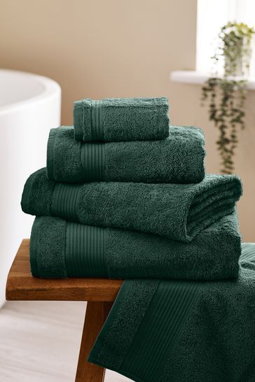 a stack of green towels sitting on top of a wooden table