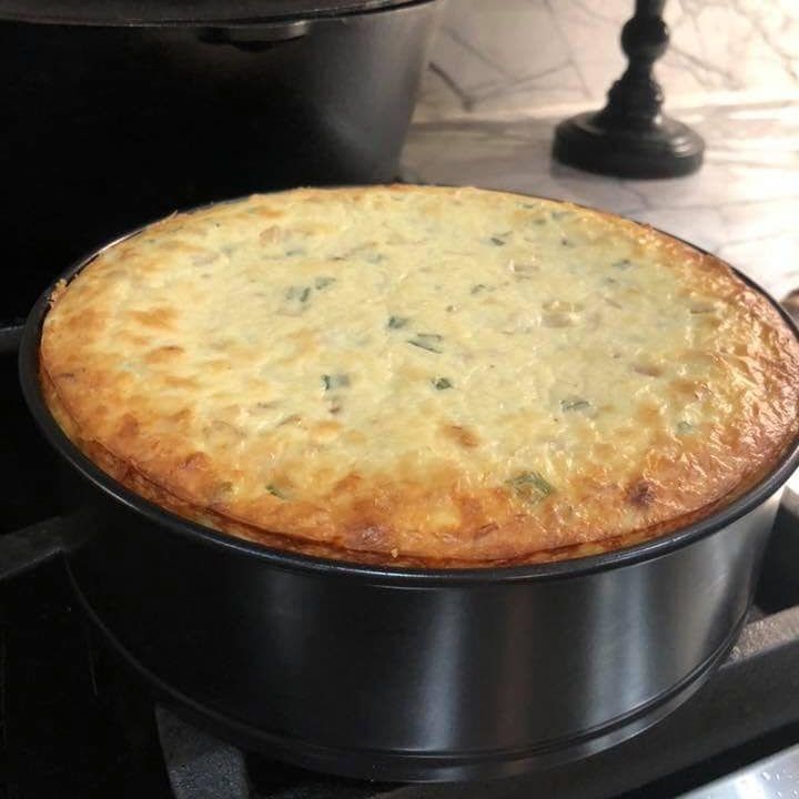 a large round cake sitting on top of a stove next to a pan filled with food