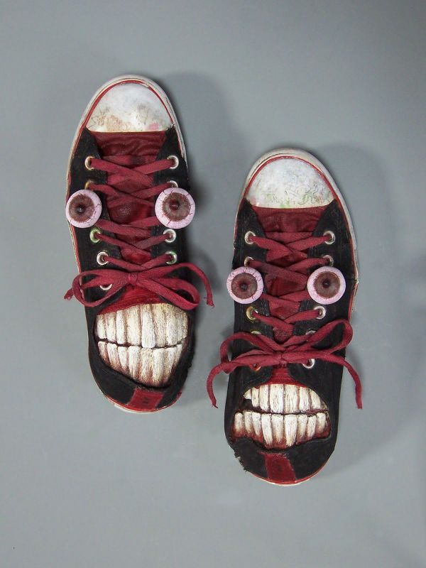 a pair of shoes with red laces on them and an evil face painted on the side