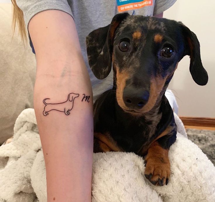 a small dachshund tattoo on the leg of a woman's arm