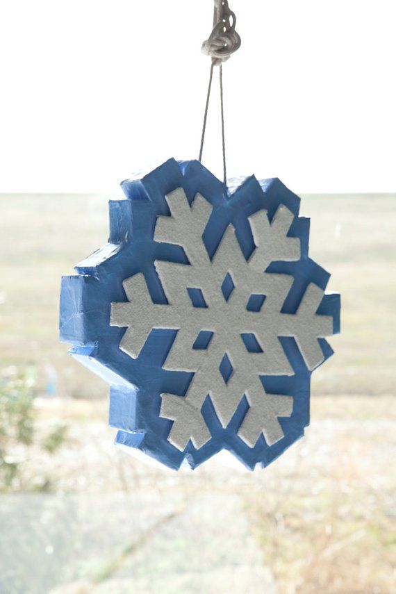 a snowflake ornament hanging from a hook in front of a window