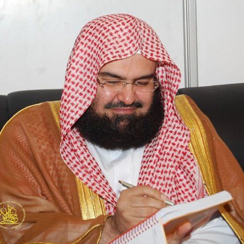 a man with a beard sitting down and writing