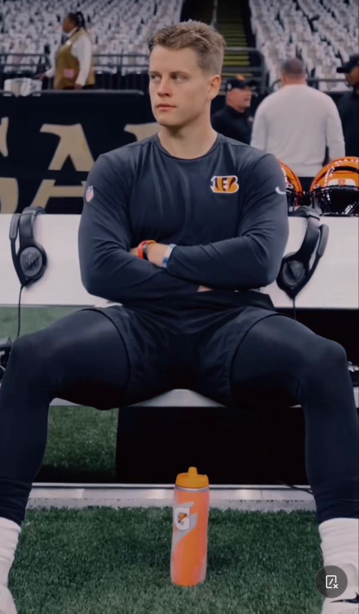 a man sitting on top of a bench in front of a stadium filled with people