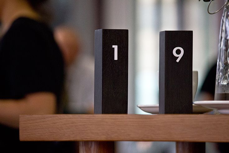 the numbers are placed on wooden blocks near a vase with flowers in it and a woman standing behind them