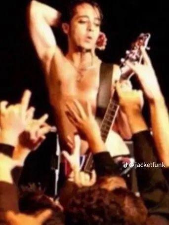 a shirtless man is holding his guitar in the air