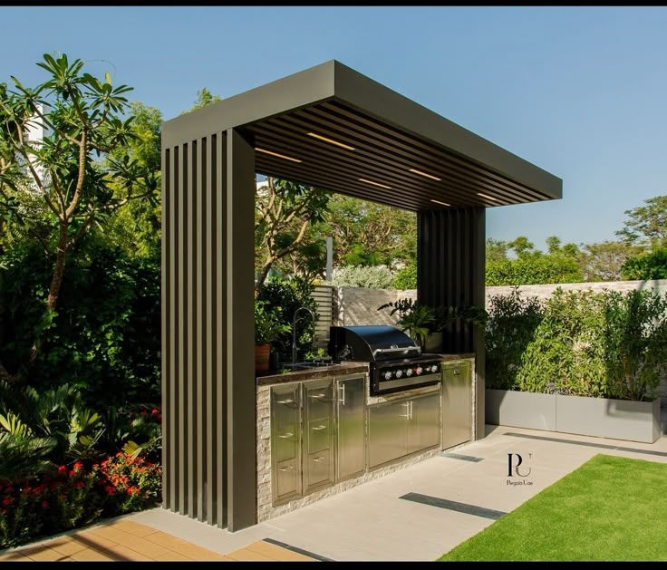 an outdoor kitchen with stainless steel appliances and grilling area, surrounded by greenery