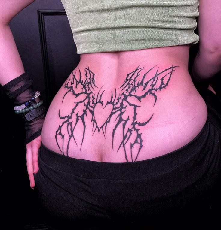 a woman's lower back tattoo with black ink