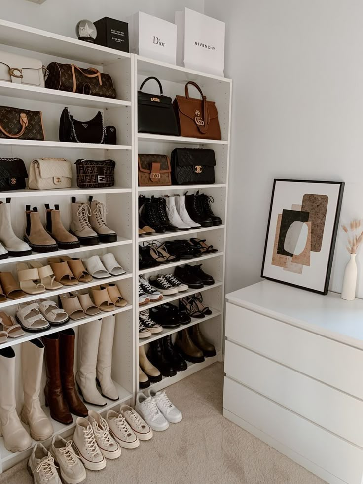 a white closet filled with lots of shoes and purses on top of shelves next to a dresser