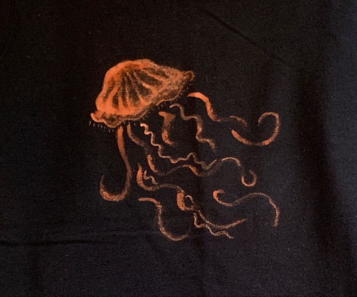 an orange jellyfish drawing on a black shirt