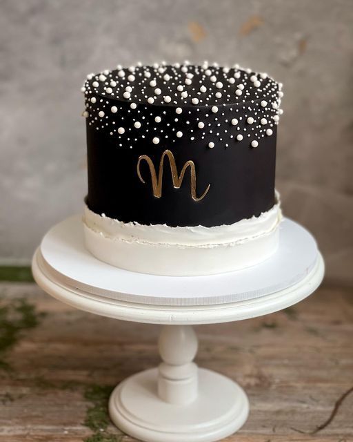 a black and white cake with gold m on top