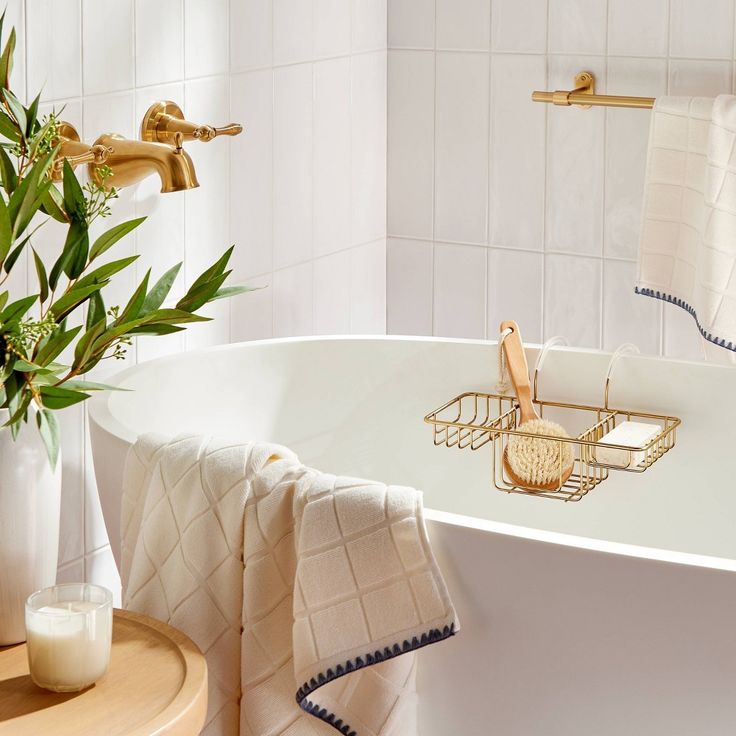 a white bath tub sitting next to a wooden table with a potted plant on it