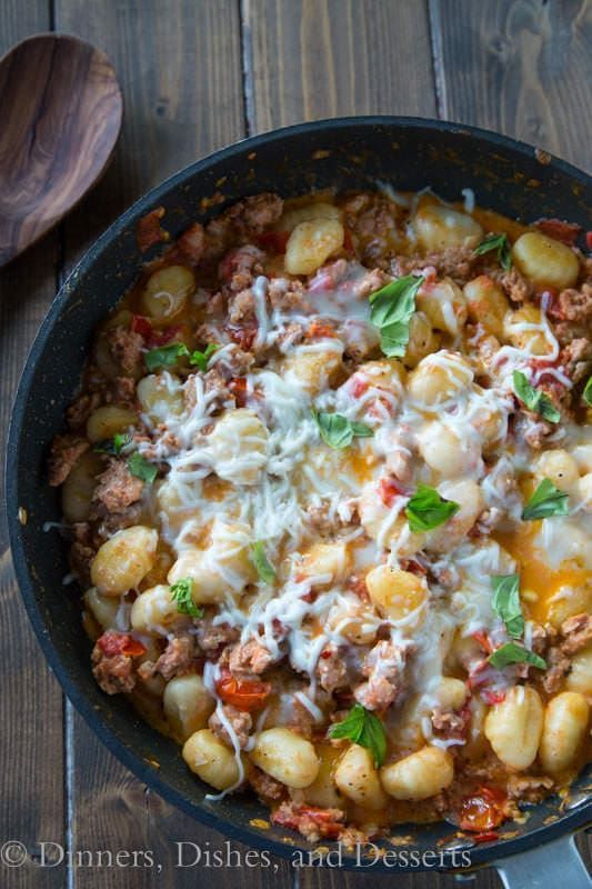 a skillet filled with pasta, meat and cheese on top of a wooden table