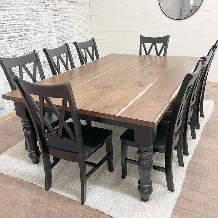 a dining room table with six chairs and a round mirror on the wall behind it