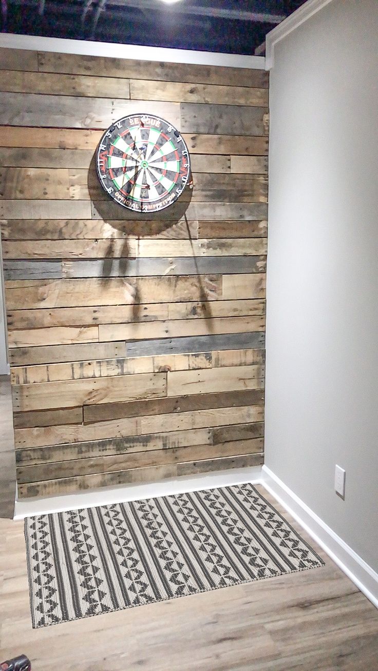 a room with a dart board on the wall and a rug in front of it